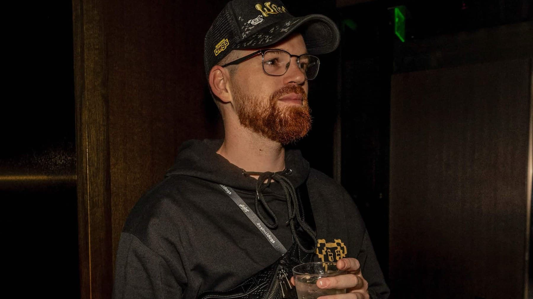 Tristun Fife (Fifi) in a Dogs hoodie and cap, holding a drink at a gathering